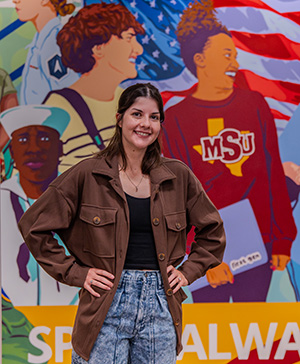artist Selena Mize stands in front of her mural "Bridging the Gap" located at MSU Texas.